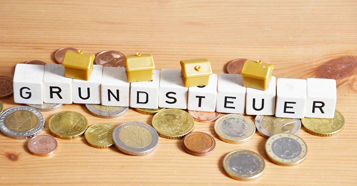 Münzen, Buchstaben und kleine Spielzeughäuser; Grundsteuer